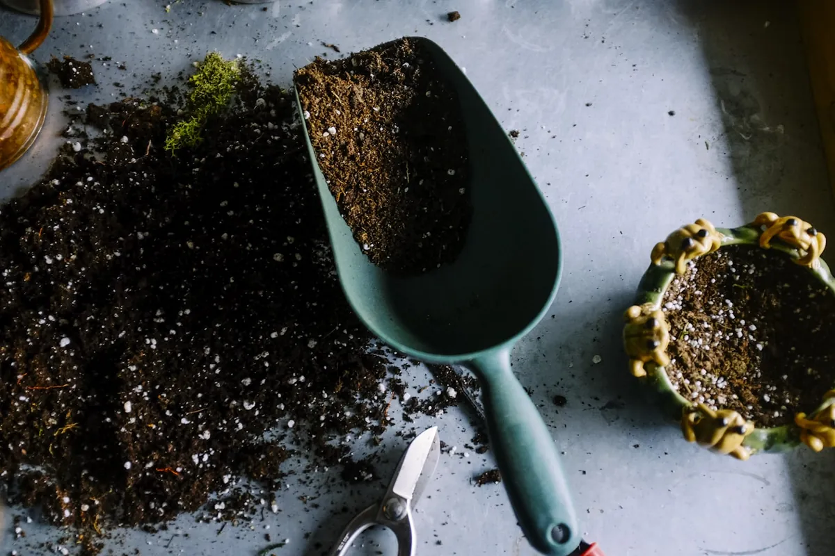 Gartenerde, Pflanzschaufel und Gartenschere auf einem Tisch